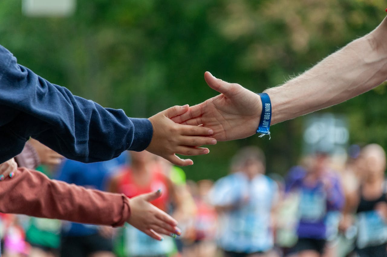 why-choose-us A runner high-fives a spectator during an outdoor marathon, symbolizing support and encouragement.